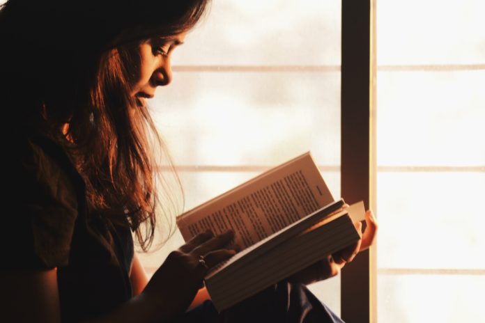 woman-reading-a-book-beside-the-window-1031588
